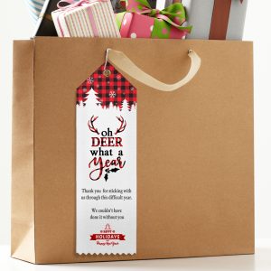 A gift bag has a custom top ribbon attached to the handle printed with a thank you to customers. 