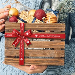 A wooden crate filled with holiday food is adorned with a ribbon.