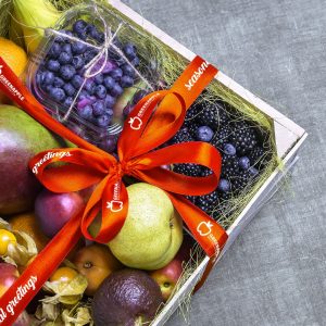 A ribbon is tied around a box filled with an assortment of fruit.