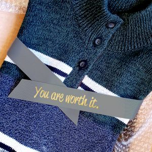 A folded sweater is wrapped with a length of ribbon.