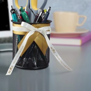 Decorated pencil holder features ribbon with imprinted text.